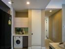 Laundry area in hallway with modern washing machine and storage