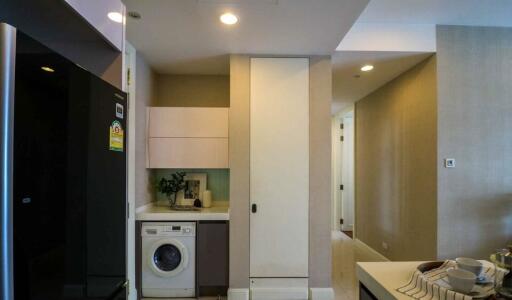 Laundry area in hallway with modern washing machine and storage