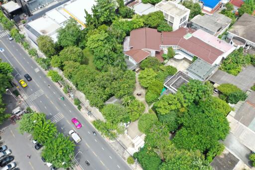 Aerial view of residential property with surrounding greenery and nearby streets