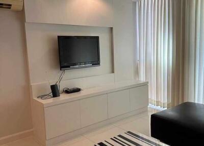 Modern living room with TV, black leather sofa, and striped coffee table