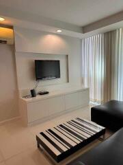 Modern living room with TV, black leather sofa, and striped coffee table