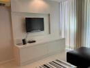 Modern living room with TV, black leather sofa, and striped coffee table