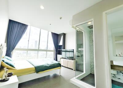 Modern bedroom with large windows, a bed, TV, and en-suite bathroom