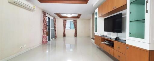 Spacious living room with TV and wooden furniture