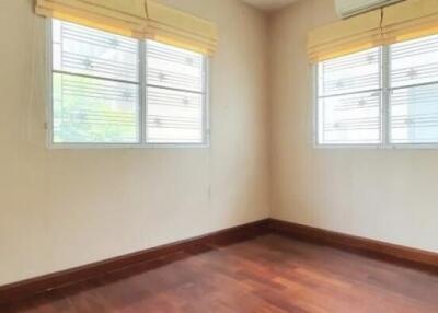 Empty bedroom with wooden floor and two windows