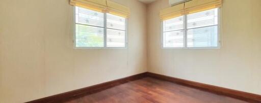 Empty bedroom with wooden floor and two windows