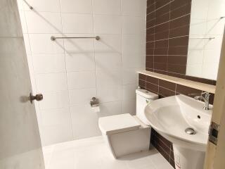 Modern white-tiled bathroom with brown accent wall