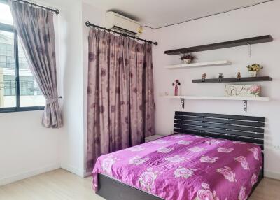 Cozy bedroom with purple floral bedding and decorative shelves
