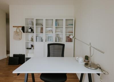 Modern home office with white desk and bookshelf