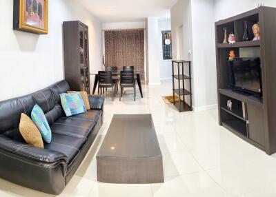 Modern living room area with black leather sofa, TV unit, and dining area