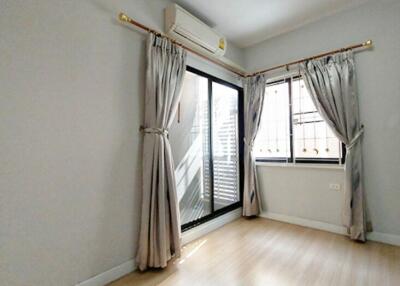 Bedroom with wooden floor, large window, and sliding door with curtains