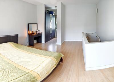 Bedroom with modern furnishings, wooden flooring, and a staircase