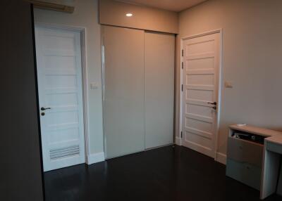 Bedroom with dark wood flooring, two white doors, and a sliding wardrobe