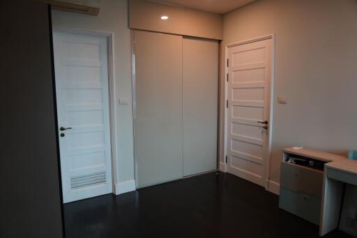 Bedroom with dark wood flooring, two white doors, and a sliding wardrobe