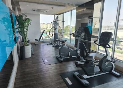 Modern gym with various exercise equipment and large windows.