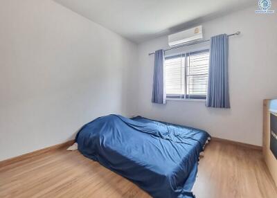 A minimalist bedroom with a mattress on the floor and an air conditioner installed