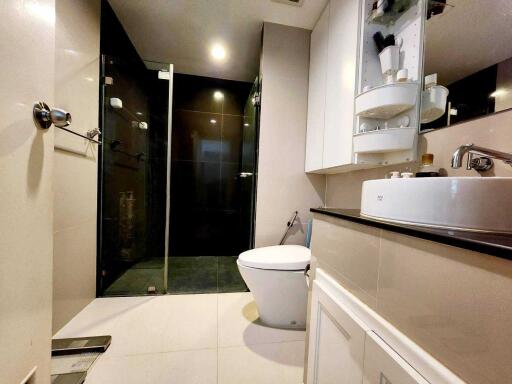 Modern bathroom with glass shower, toilet, and sink