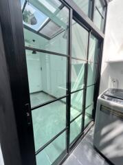 Glass-enclosed utility room with washing machine and skylight