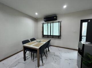 A well-lit dining area with a modern table and chairs set in a room with tiled flooring.