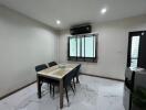 A well-lit dining area with a modern table and chairs set in a room with tiled flooring.