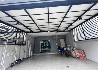 Covered garage with a motorcycle and storage items