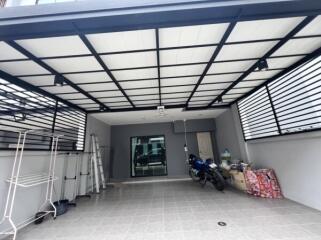 Covered garage with a motorcycle and storage items