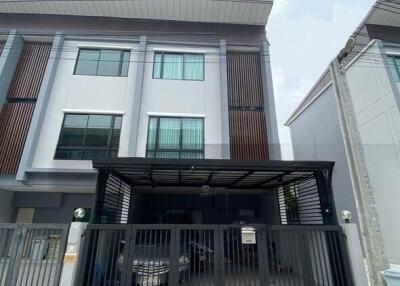 Front view of a modern townhouse with a gated parking area