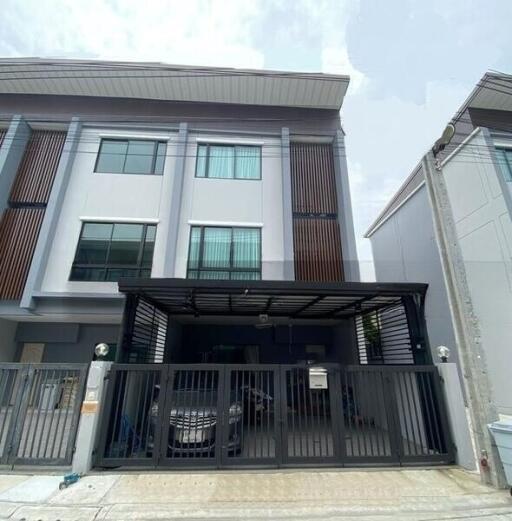 Front view of a modern townhouse with a gated parking area