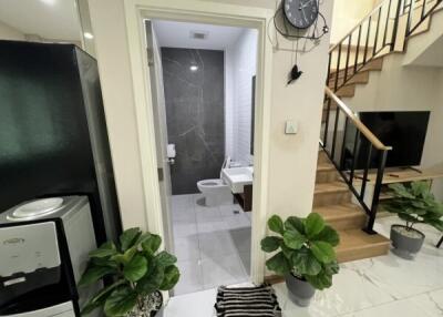 Entrance to modern bathroom with black and white tiles, next to staircase and black appliances