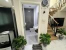 Entrance to modern bathroom with black and white tiles, next to staircase and black appliances