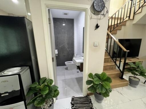 Entrance to modern bathroom with black and white tiles, next to staircase and black appliances