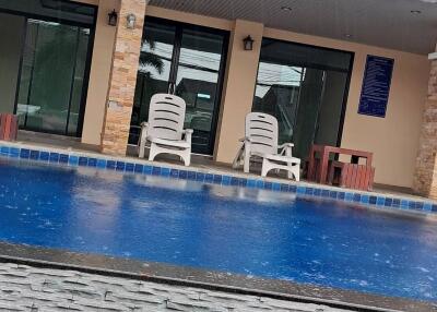 Swimming pool with poolside chairs and adjoining building