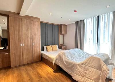 Modern bedroom with large window, wooden flooring, and built-in wardrobe