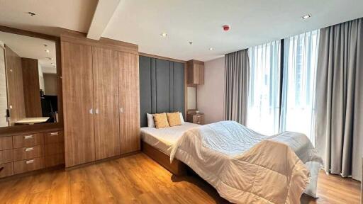 Modern bedroom with large window, wooden flooring, and built-in wardrobe