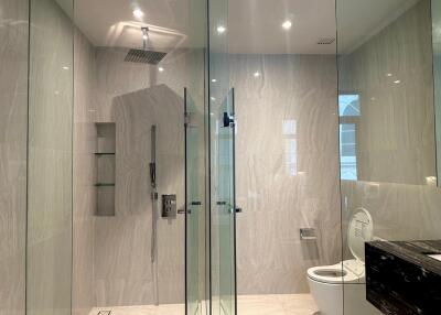 Modern bathroom with glass-enclosed shower and toilet.