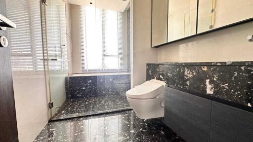 Modern bathroom with large windows, black marble floor, and wall-mounted toilet