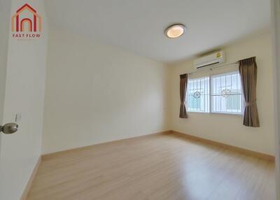 Bright bedroom with wooden floor, air conditioning, and large window with curtains