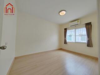 Bright bedroom with wooden floor, air conditioning, and large window with curtains