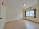 Bright bedroom with wooden floor, air conditioning, and large window with curtains