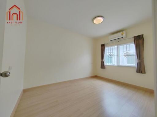 Bright bedroom with wooden floor, air conditioning, and large window with curtains