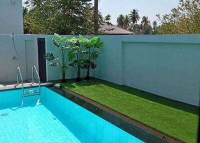 Swimming pool area with palm trees and green grass
