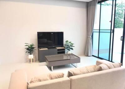 Modern living room with sofa, TV, and large windows