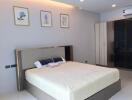 Modern bedroom with bed, wardrobe, framed paintings, and air conditioning