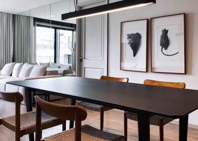 Modern dining room with wooden chairs, black dining table, and cozy living area