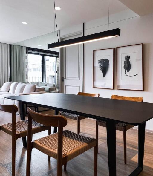 Modern dining room with wooden chairs, black dining table, and cozy living area