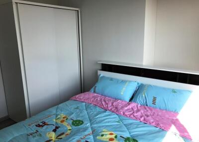 A neatly arranged bedroom with a wardrobe and a bed with colorful bedding.