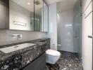 Modern bathroom with black marble countertop and glass shower