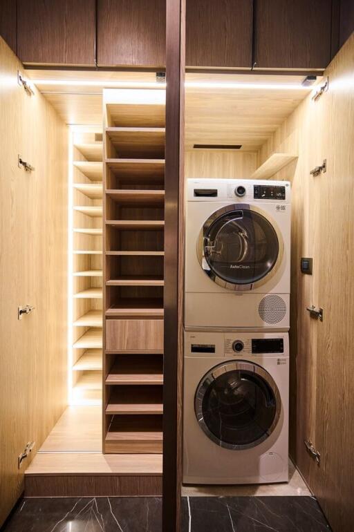 Modern laundry room with washer and dryer stacked neatly inside wooden cabinetry