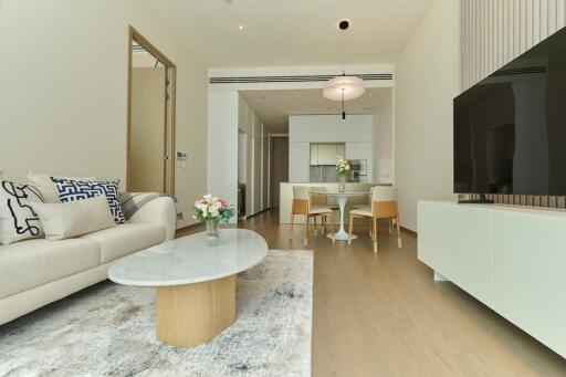 Modern living room with adjacent dining area, featuring neutral tones and contemporary furniture