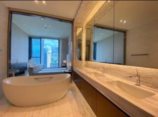 Modern bathroom with a freestanding bathtub, double sinks, and large mirrors